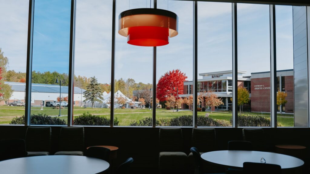 View through a large window overlooking Thomas College quad and Ayotte Center.