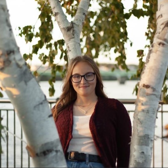 person sitting against a tree and smiling
