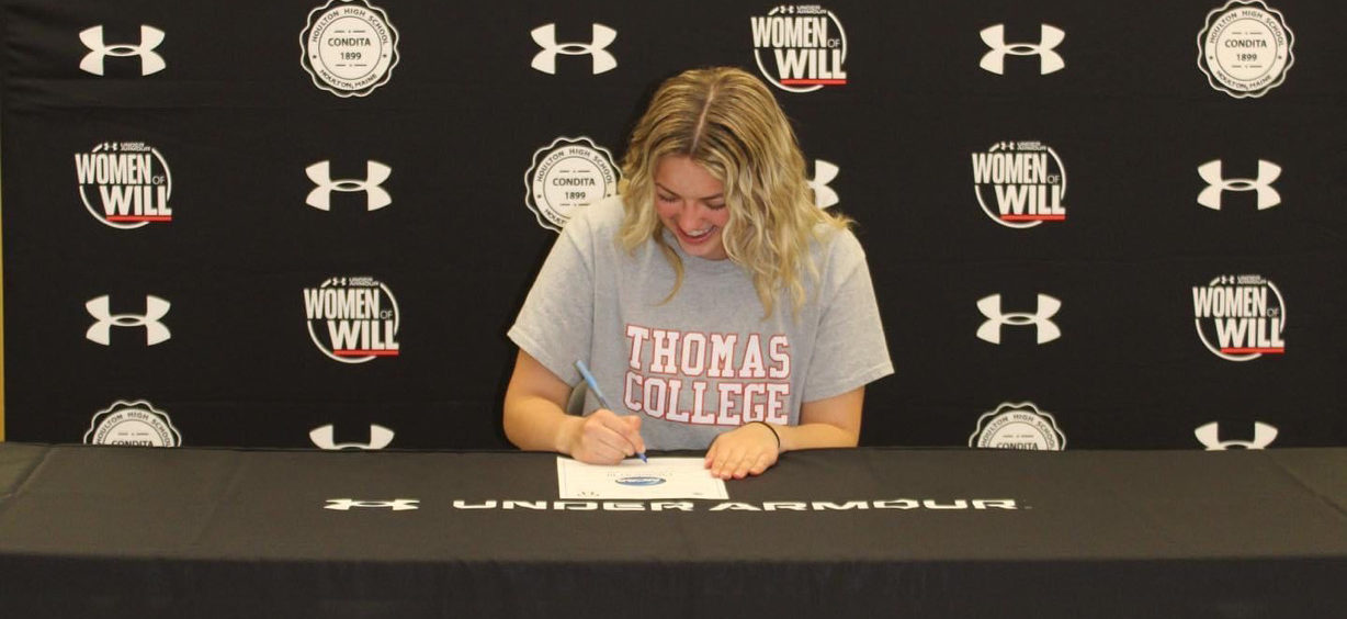 person sitting at desk and signing a piece of paper