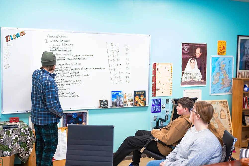 Maine School of Science and Mathematics (MSSM) Students looking at a whiteboard while their colleague writes