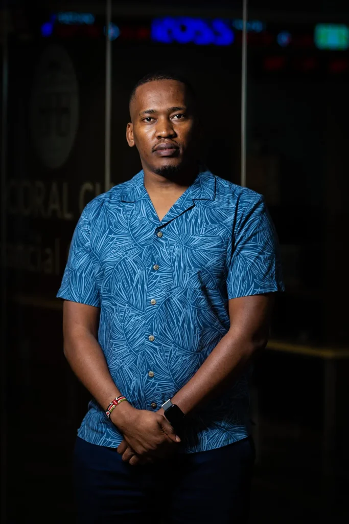Laban Moian Nyangau standing in front of a dark finance lab on campus