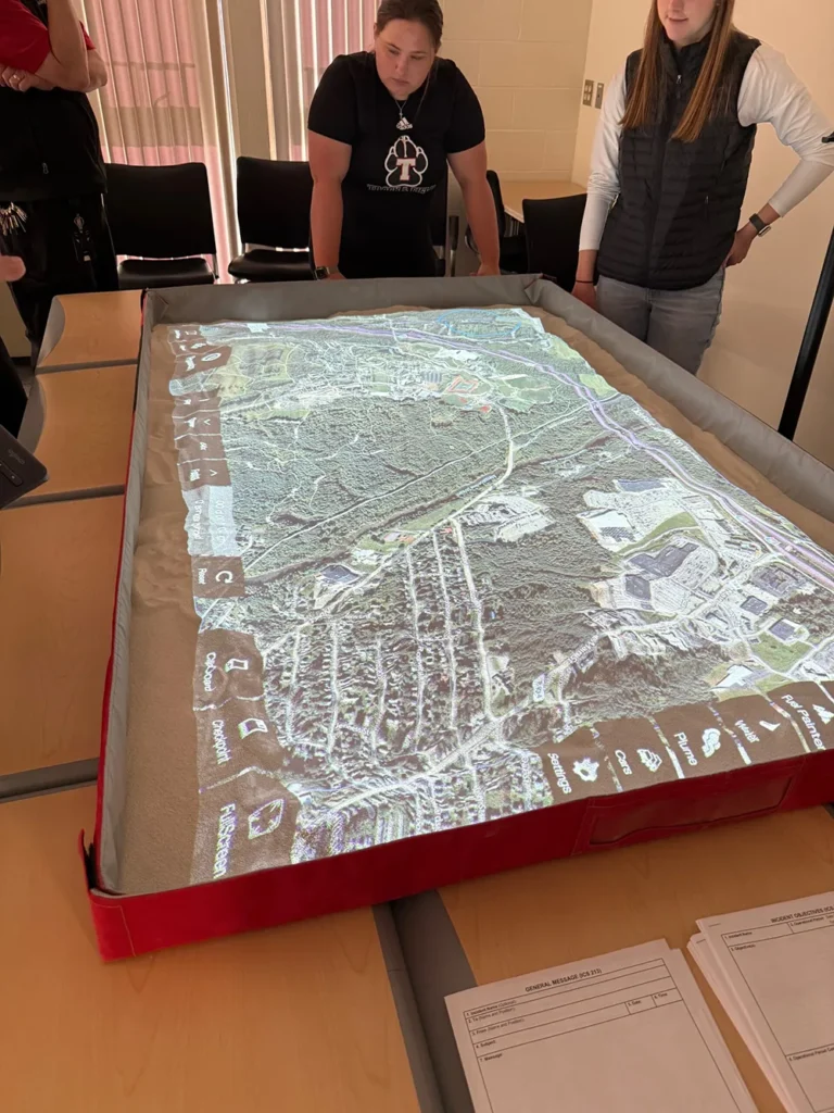 A digital view of the town of Waterville is lit up on a table called the simulation table