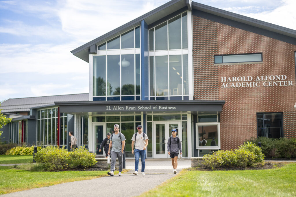 Thomas College students walking on campus in front of the Alfond Academic Center building during early fall