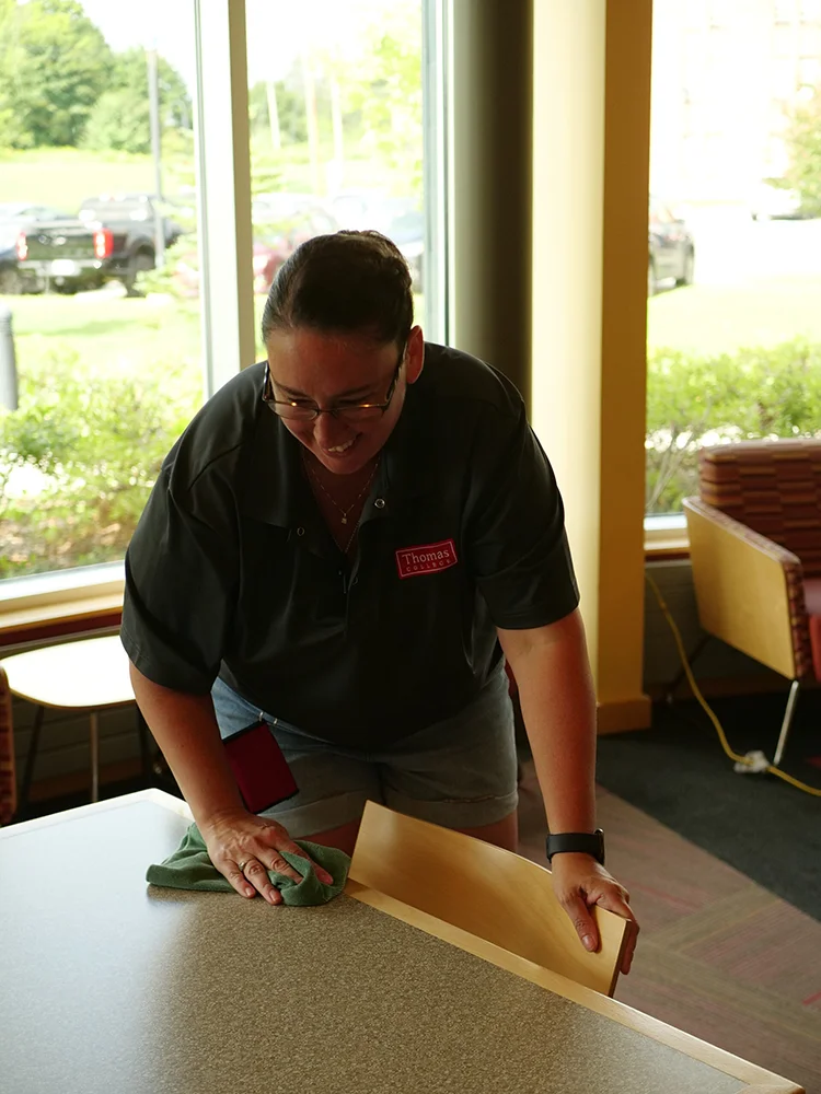 Jenn Field lead custodian cleaning tables on campus
