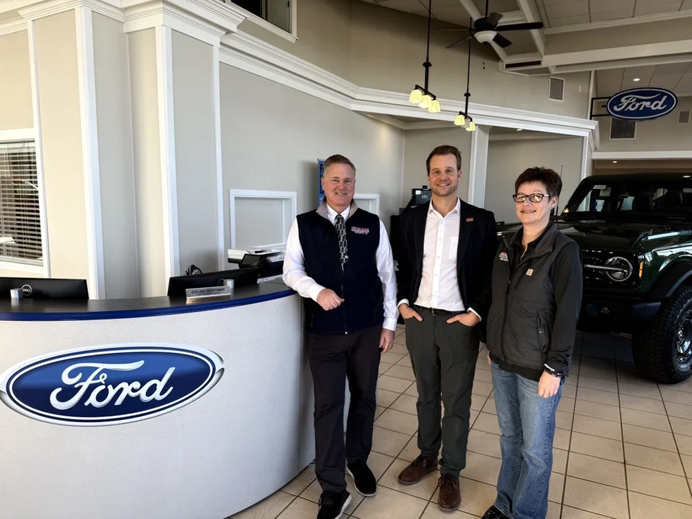 Central Maine Motors CEO and HR Director stand with Thomas College's Nate Pelsma at Central Maine Motors. They are partnering together to offer professional development to their employees as part of Thomas College's Corporate Campus.