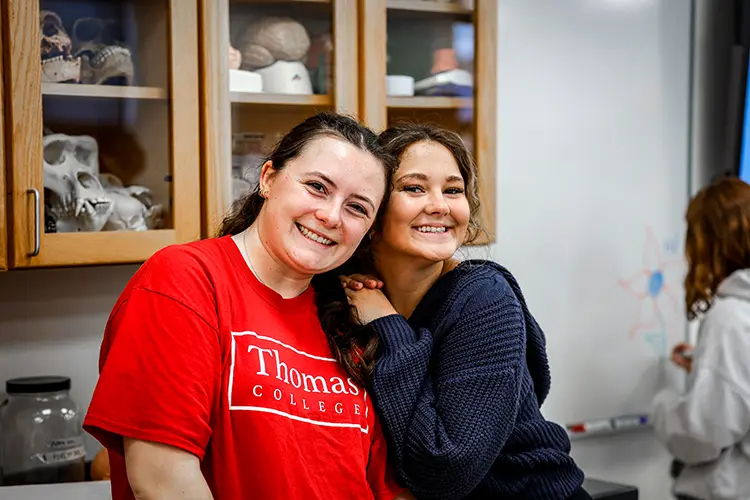 Thomas College student Alexis Spencer poses next to another student in a science lab during a Girls in Science event at Thomas College