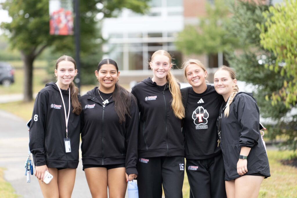 a group of students posing on campus wearing athletics gear