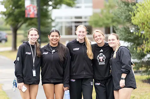 a group of students posing on campus wearing athletics gear