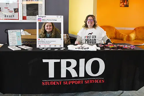 Two women sitting at a table promoting the TRIO program at Thomas College