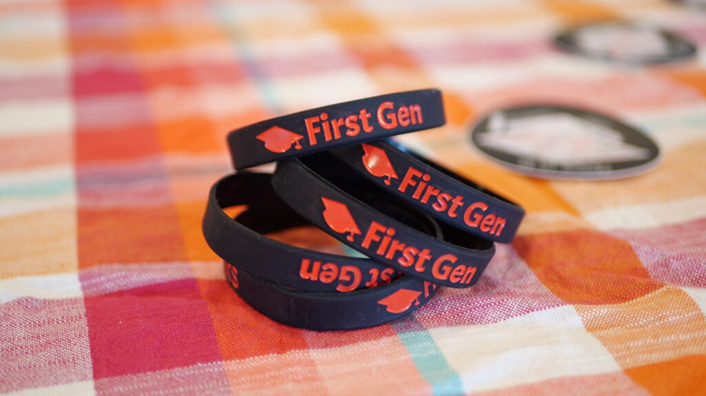 A stack of rubber bracelets that read "First Gen" sitting on a table
