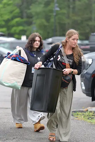 An entering student and their family holding items to move into a residence hall
