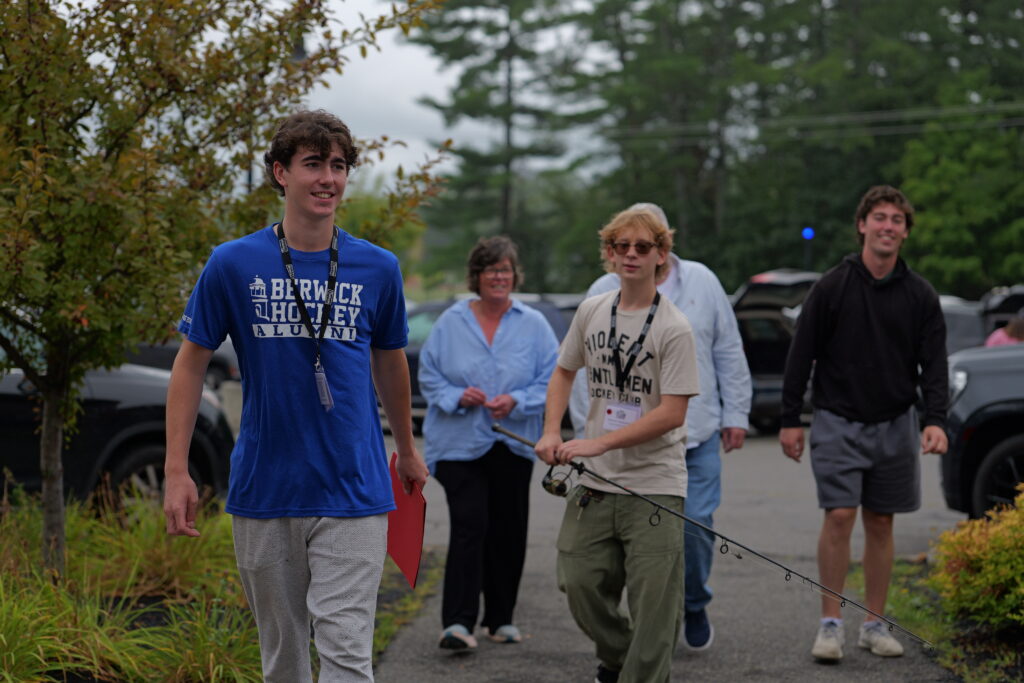 An entering student and their family holding items to move into a residence hall