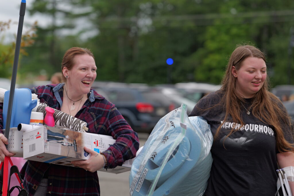 an entering student and her parent holding items to move into a residence hall