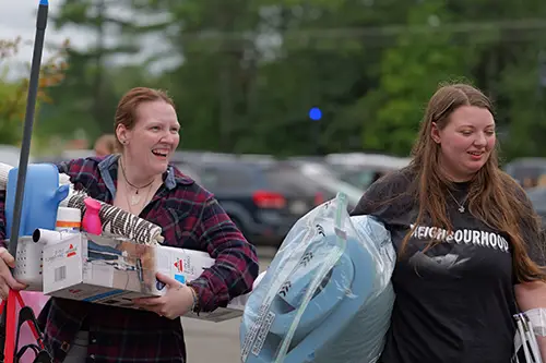 an entering student and her parent holding items to move into a residence hall