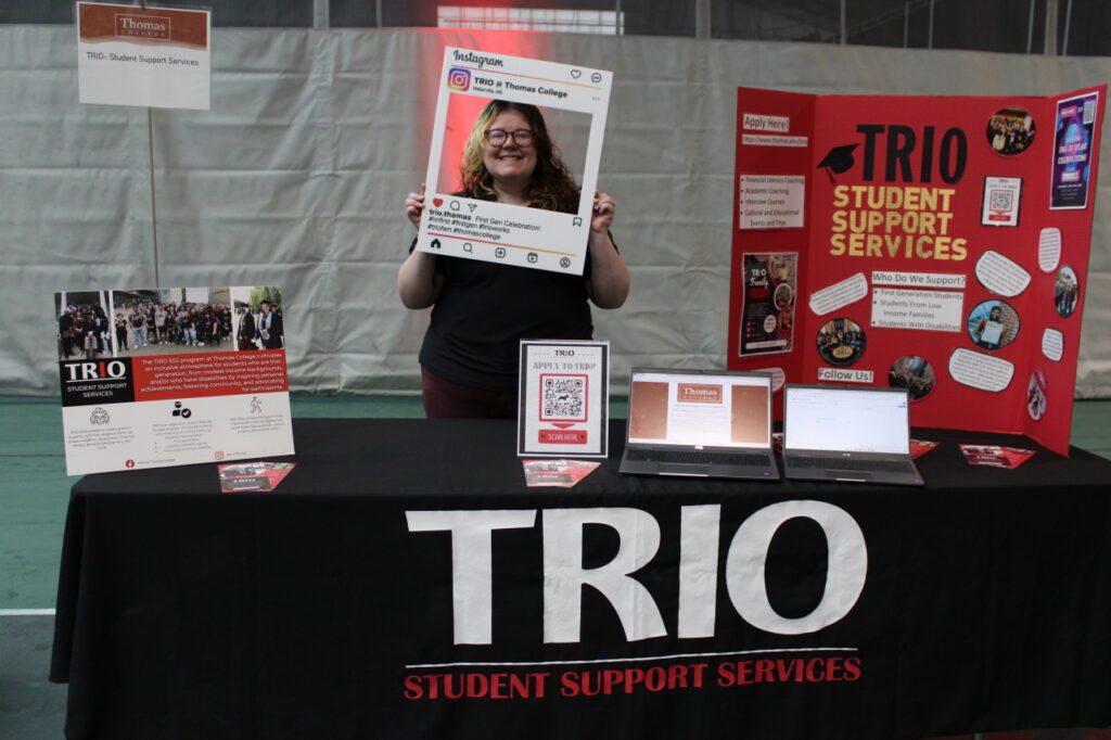 TRIO director Lexie holding up a sign at a TRIO table at Thomas College
