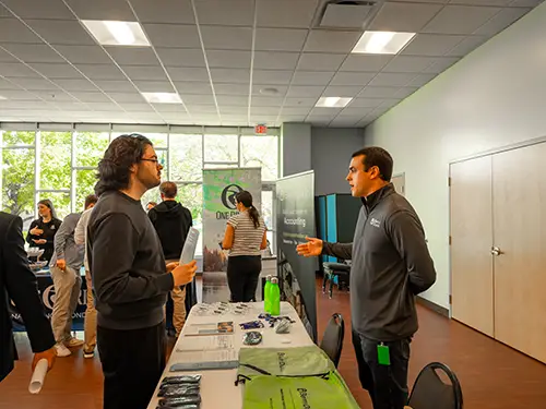 A Thomas College student stands to the left listening to the accounting staff member on the right during accounting firm night